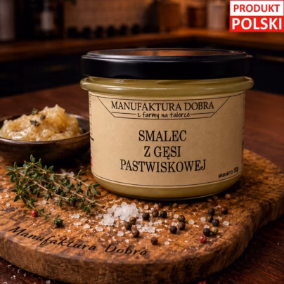 Smalec z gęsi pastwiskowej Manufaktura Dobra w szklanym słoiku na drewnianej desce z tymiankiem, pieprzem i solą, w rustykalnym kuchennym wnętrzu.