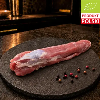 Surowa polędwica wieprzowa puławska na czarnej desce, podana z ziarnami pieprzu.