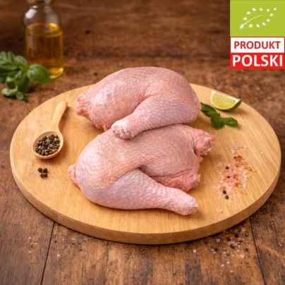 Dwie surowe ćwiartki z kurczaka pastwiskowego EKO ze skórą, ułożone na drewnianej desce z pieprzem, solą himalajską, limonką i bazylią