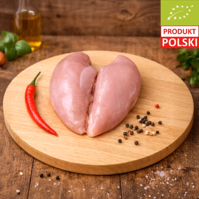 Pierś z kurczaka ekologicznego — dwa surowe filety z kurczaka pastwiskowego ułożone na drewnianej desce z papryczką chili, kolorowym pieprzem i świeżą bazylią
