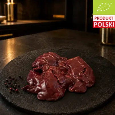 Surowa wątróbka z kurczaka pastwiskowego na czarnej desce, podana z ziarnami pieprzu.