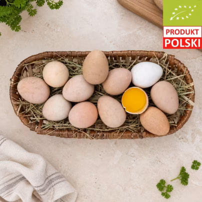 Jaja perlicze 6 sztuk EKO w wiklinowym koszyku z sianem, z rozbitym jajem ukazującym intensywnie pomarańczowe żółtko z certyfikowanej hodowli pastwiskowej